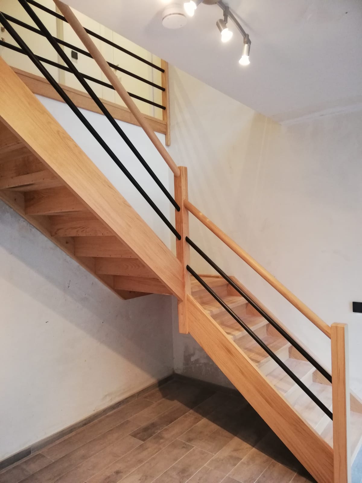 Gesloten kwartdraaitrap met palier in Rubberwood gecombineerd met balustrade inox zwart gelakt en hout